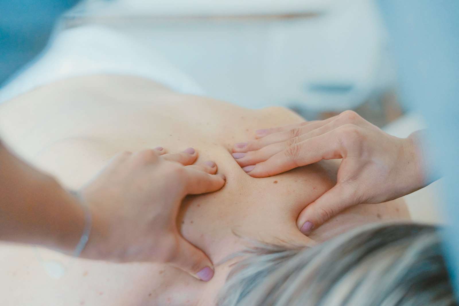 Fisioterapeuta aplicando terapia manual en los hombros y la espalda alta de una paciente