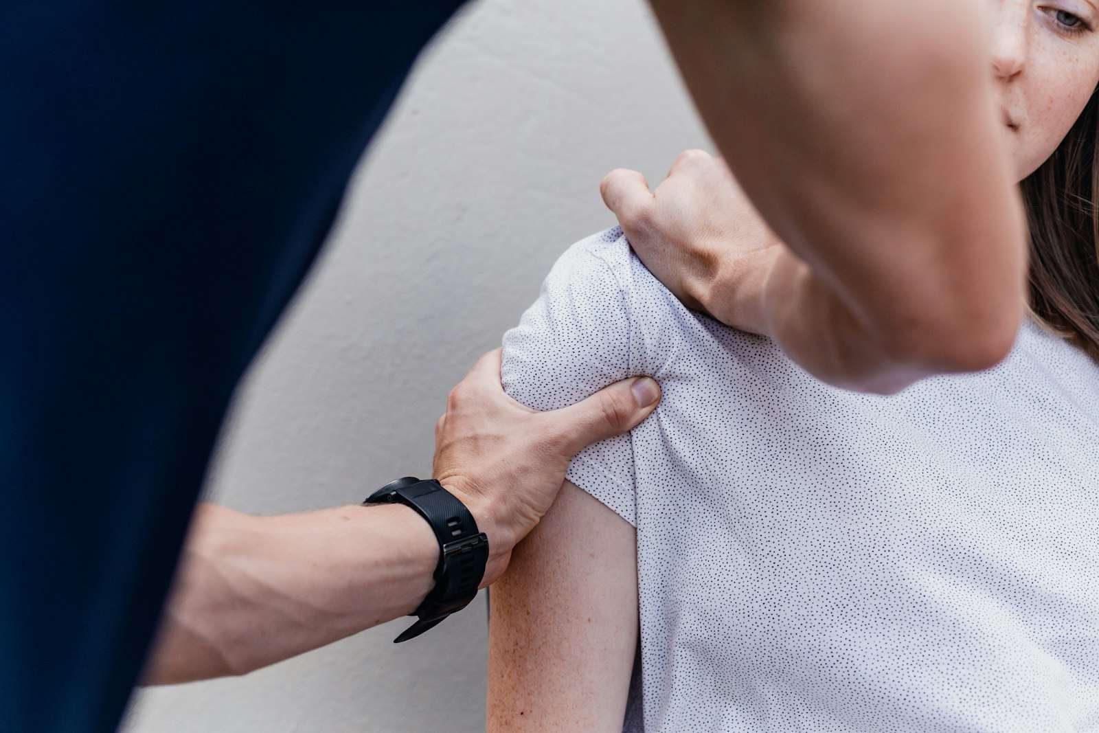 Fisioterapeuta movilizando el hombro de una paciente sentada