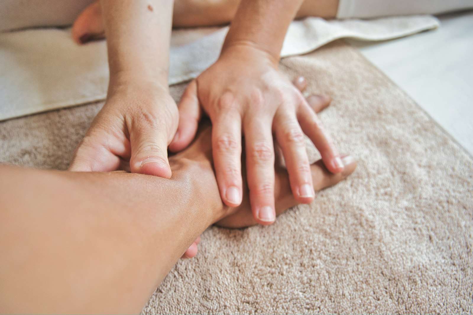Manos de una fisioterapeuta trabajando suavemente el antebrazo de un paciente