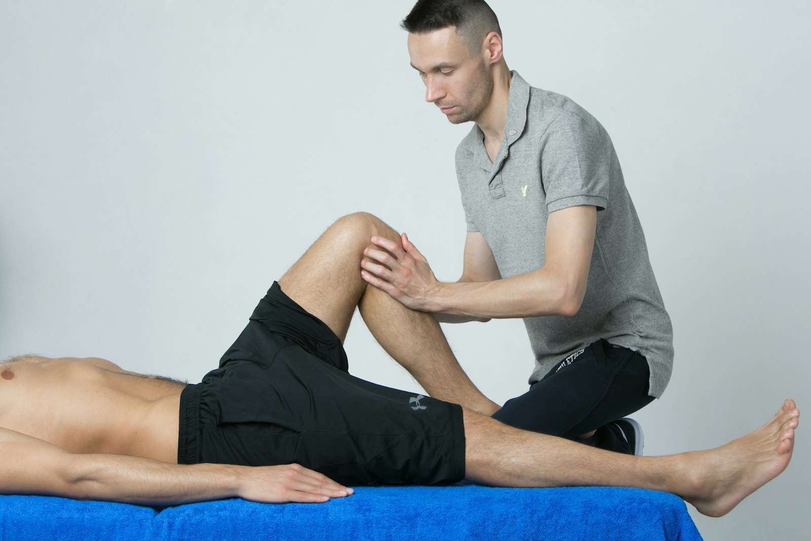 Fisioterapeuta evaluando la rodilla de un paciente recostado en una camilla